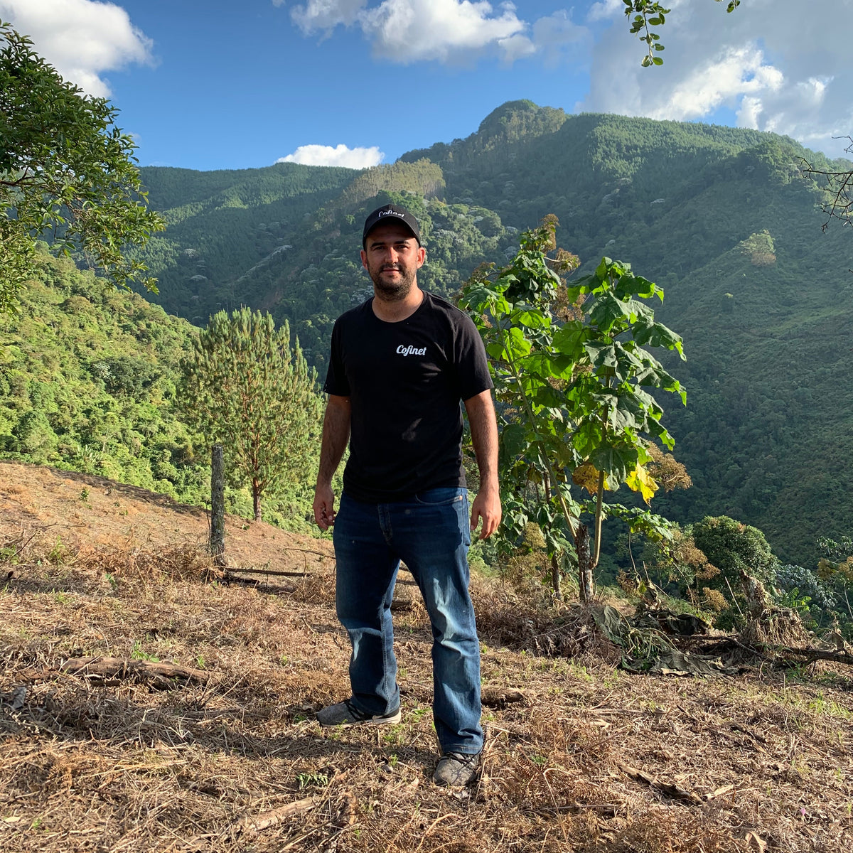JARDINES DEL EDEN PAPAYO producer standing in Colombian landscape with lush mountains in the background.
