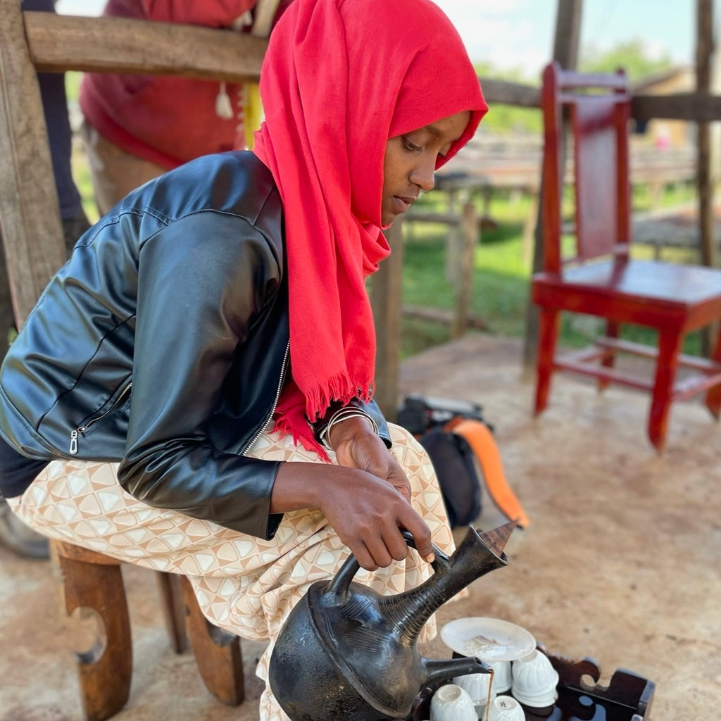 Traditional Ethiopian coffee ceremony with coffee being poured from a jebena into small cups.