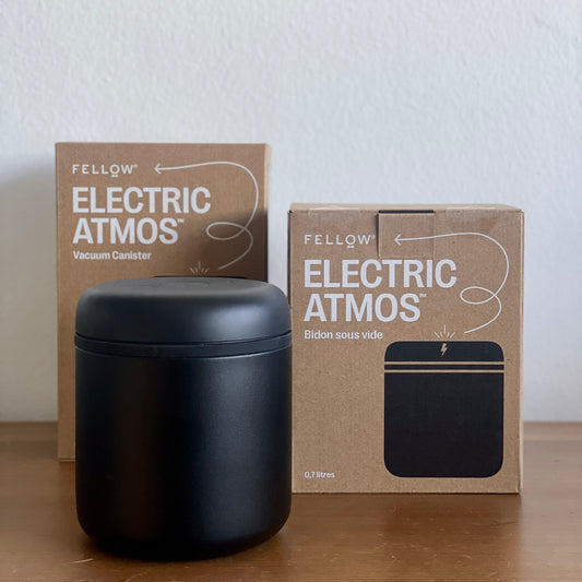 ATMOS ELECTRIC VACUUM CANISTER displayed alongside its packaging on a wooden table.