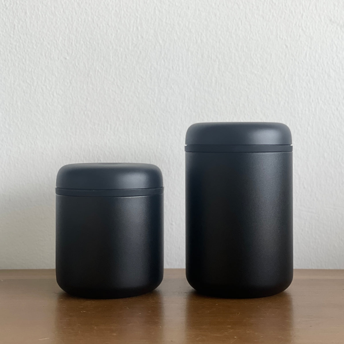 ATMOS ELECTRIC VACUUM CANISTER in matte black, showcasing two sizes on a wooden surface.