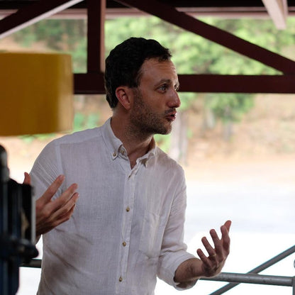 Person explaining the unique qualities of VOLCAN AZUL GESHA HONEY in a coffee estate setting.