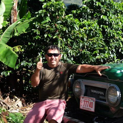 Coffee farmer standing next to a green Toyota Land Cruiser in a coffee plantation