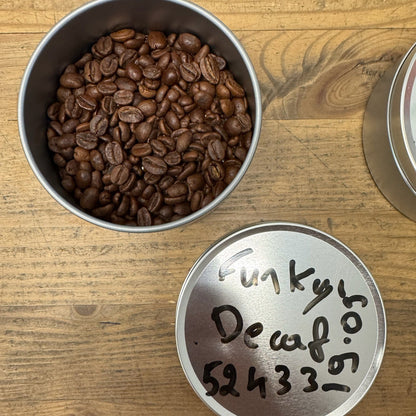 DECAF FUNKY coffee beans in a tin on a wooden surface, showcasing the vibrant Colombian flavor profile.