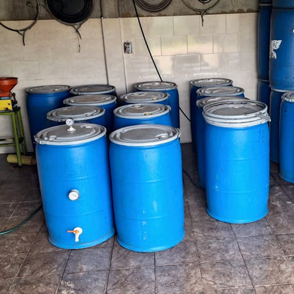 Row of coffee storage blue barrels with metal lids in a storage area.