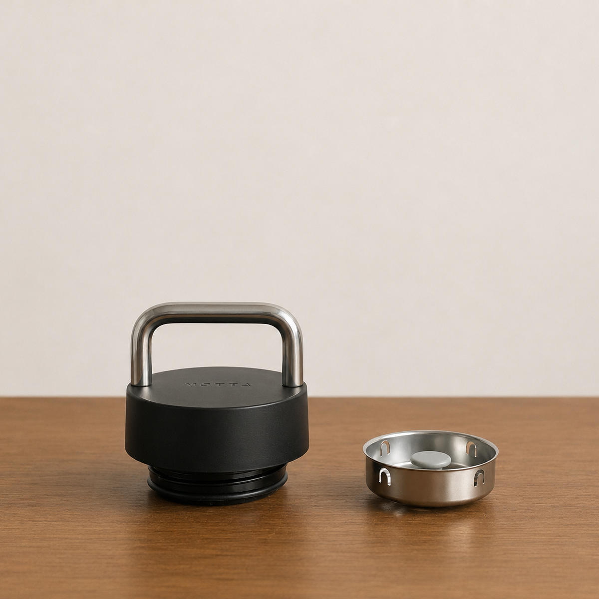 FELLOW CARTER CARRY TUMBLER lid with stainless steel handle on a wooden table, designed for coffee lovers.