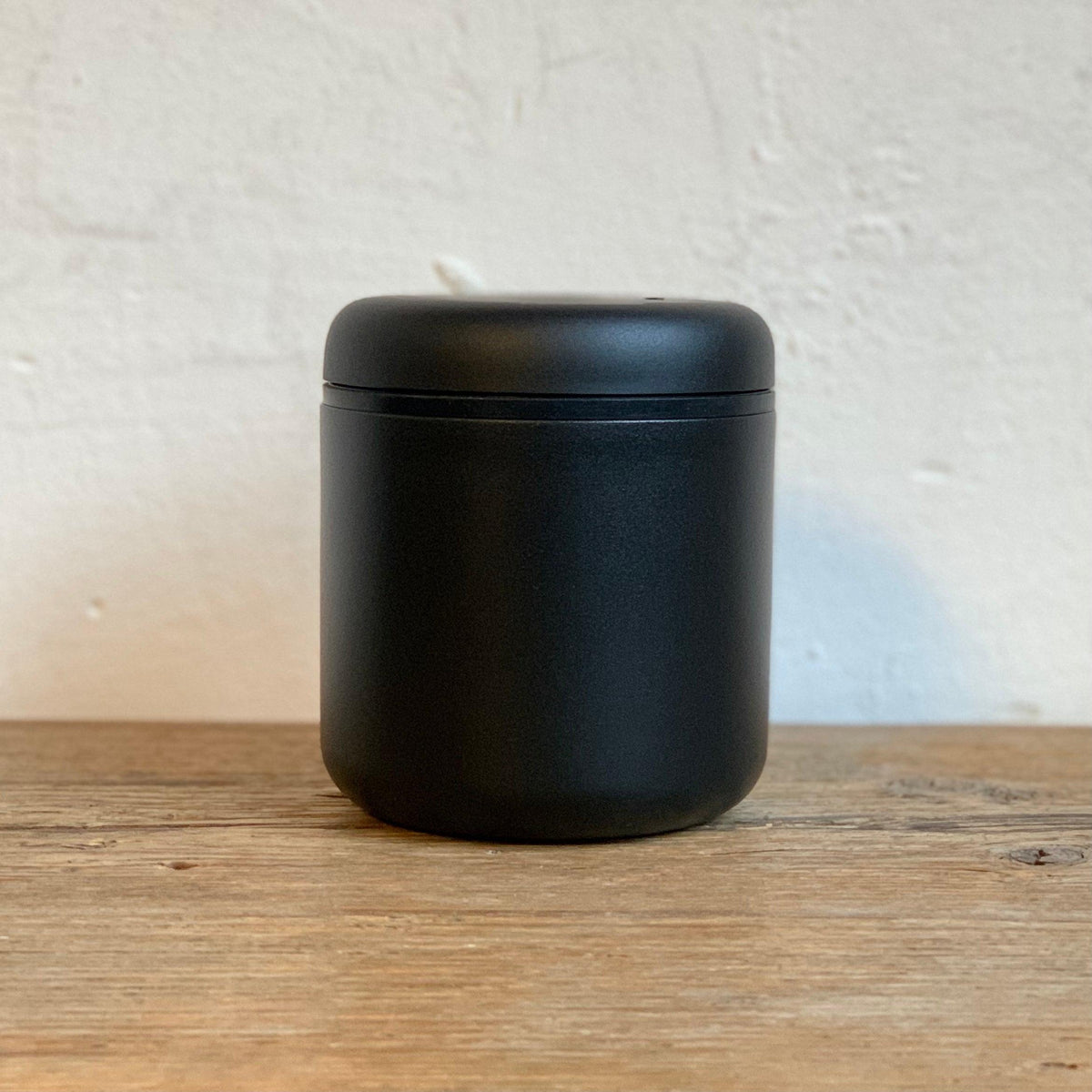 ATMOS ELECTRIC VACUUM CANISTER in matte black stainless steel on wooden surface.