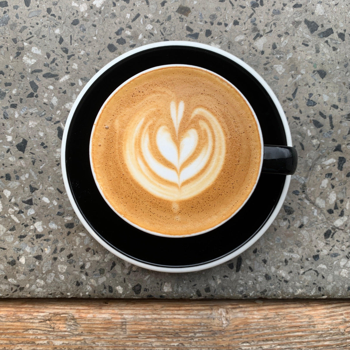 OFFICE COFFEE SUBSCRIPTION - beautifully crafted latte art in a black cup on a textured surface.